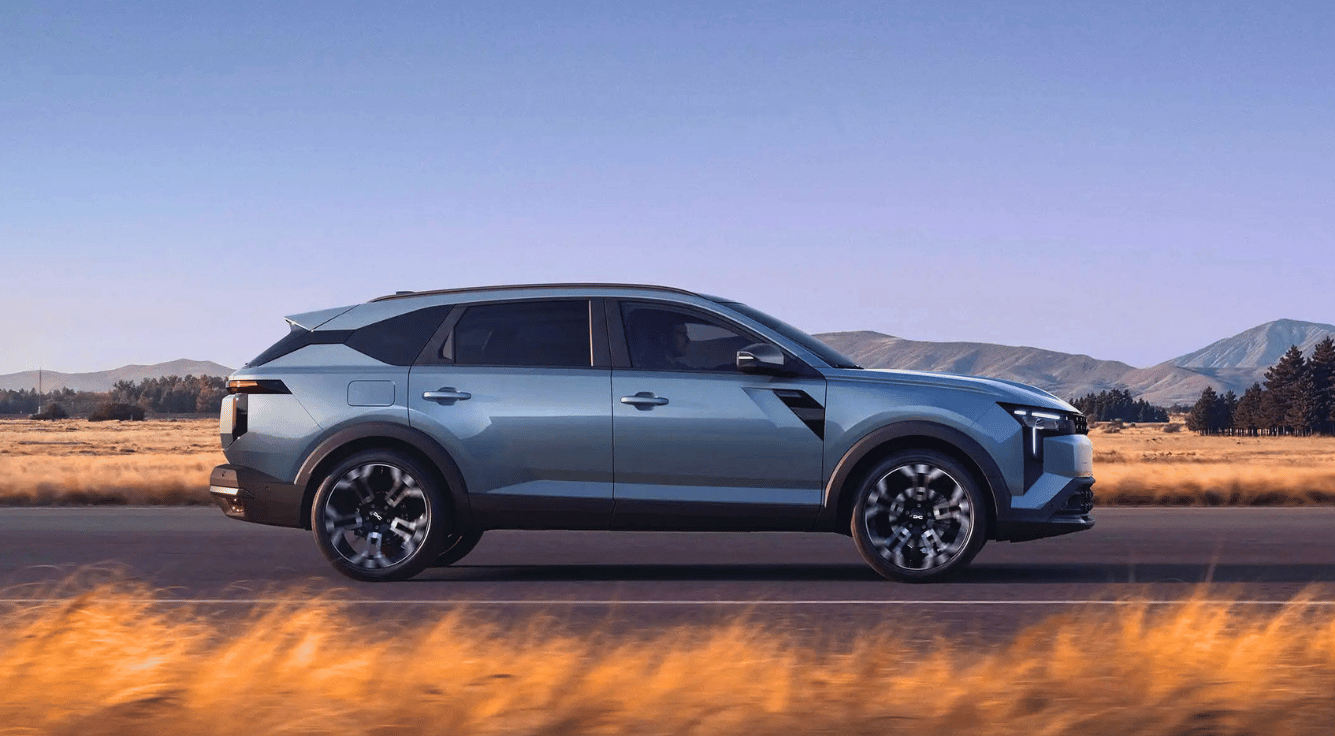 Auto: Dacia Striker in graublau metallic, fahrend auf der Straße, seitlich, Hintergrund Berge, Wald