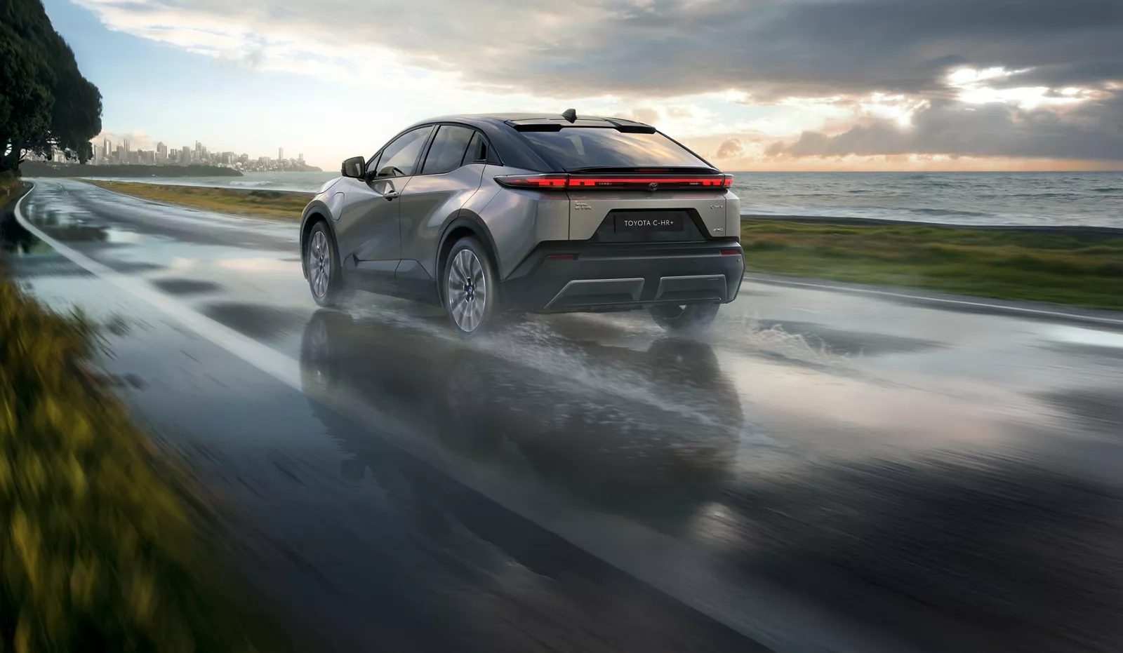 Auto, C-HR+ auf der nassen Straße fahrend